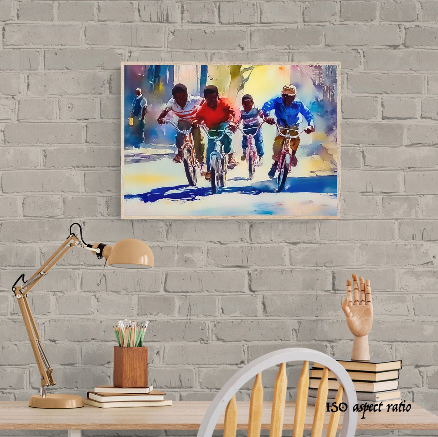 Colorful painting of children on bicycles hanging on a gray brick wall above a desk.